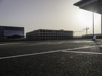 the man is taking a photo in an empty parking lot outside of a building at sunset