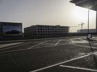 the man is taking a photo in an empty parking lot outside of a building at sunset