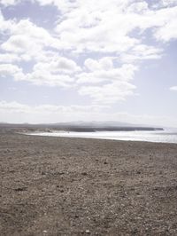 a man walking along a sandy beach with a red and blue kite flying in the sky
