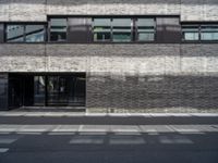 a man is walking up the sidewalk in front of a building with windows and signage