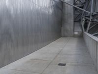 a man with a helmet and black jacket is walking near a wall of metal walls