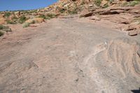 a man is walking on an old road in the desert side way next to a steep hill