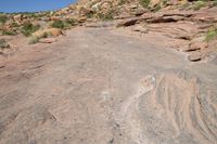 a man is walking on an old road in the desert side way next to a steep hill