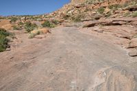 a man is walking on an old road in the desert side way next to a steep hill