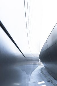 a man walking on the side of a road near a metallic wall of a building