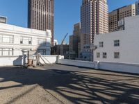 the man is walking down a rooftop with a cart behind him and buildings beyond them