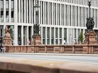 a man walks across the street in front of a stone lion statue and some building