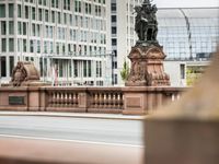 a man walks across the street in front of a stone lion statue and some building