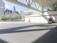 a man walking down the street near a train station on the tracks passing underneath the walkway