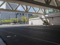 a man walking down the street near a train station on the tracks passing underneath the walkway