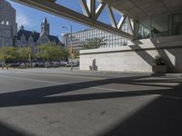 a man walking down the street near a train station on the tracks passing underneath the walkway