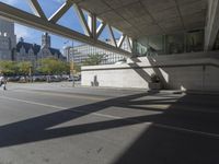 a man walking down the street near a train station on the tracks passing underneath the walkway