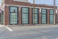 a man with a skateboard walks down the street by a store and a brick building