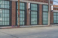 a man with a skateboard walks down the street by a store and a brick building