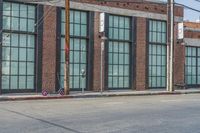 a man with a skateboard walks down the street by a store and a brick building