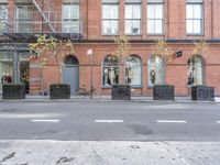 an empty street and bicycle parked outside of a store front window and behind planters