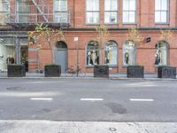 an empty street and bicycle parked outside of a store front window and behind planters