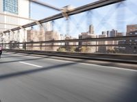 a person on a motorcycle crossing a bridge that is mostly empty and clear of traffic