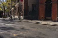 a person on a bicycle rides through the street in front of buildings and trees,