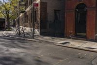 a person on a bicycle rides through the street in front of buildings and trees,