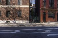 a bike is sitting on the curb beside a red brick building and sidewalk in a sunny day