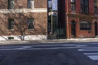 a bike is sitting on the curb beside a red brick building and sidewalk in a sunny day