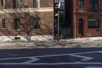 a bike is sitting on the curb beside a red brick building and sidewalk in a sunny day