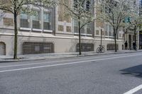 two trees in front of a brick building next to a street with bicycles parked on it