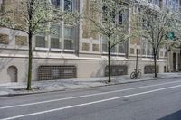 two trees in front of a brick building next to a street with bicycles parked on it