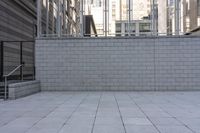 a brick and steel fence stands at the top of a building and a ramp leads up to an entrance