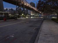 an empty road on a city street near the water at night, with streetlights glowing down