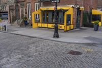 the corner of the street shows a yellow restaurant with an awning over it and no cars