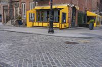 the corner of the street shows a yellow restaurant with an awning over it and no cars