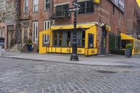 the corner of the street shows a yellow restaurant with an awning over it and no cars