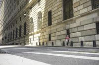 a person walking across a cross walk by a building with tall windows in the background