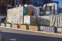 a row of graffiti covered planters on the side of a street near an alley