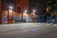 some graffiti and bicycle parking along the street in the dark night time area of an urban city