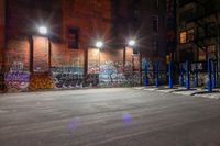 some graffiti and bicycle parking along the street in the dark night time area of an urban city