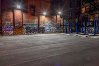 some graffiti and bicycle parking along the street in the dark night time area of an urban city