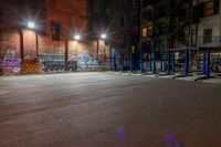 some graffiti and bicycle parking along the street in the dark night time area of an urban city