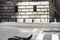 the man is walking on the sidewalk in the city setting and crossing the street corner