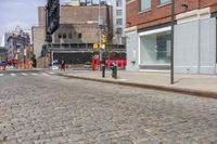 a road is seen at the corner of a street and is full of brick sidewalks with red traffic signals