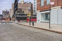 a road is seen at the corner of a street and is full of brick sidewalks with red traffic signals