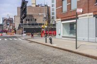 a road is seen at the corner of a street and is full of brick sidewalks with red traffic signals