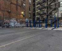 a street corner with several parking lot stands by graffiti covered buildings and staircases above