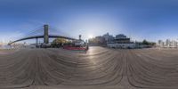 a fish eye lens with buildings in the background and people walking and sitting on the pier