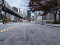 a empty street with a bridge over the river and an overpass at the end