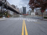 a empty street with a bridge over the river and an overpass at the end