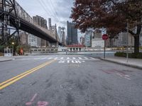 a empty street with a bridge over the river and an overpass at the end