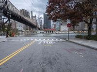 a empty street with a bridge over the river and an overpass at the end